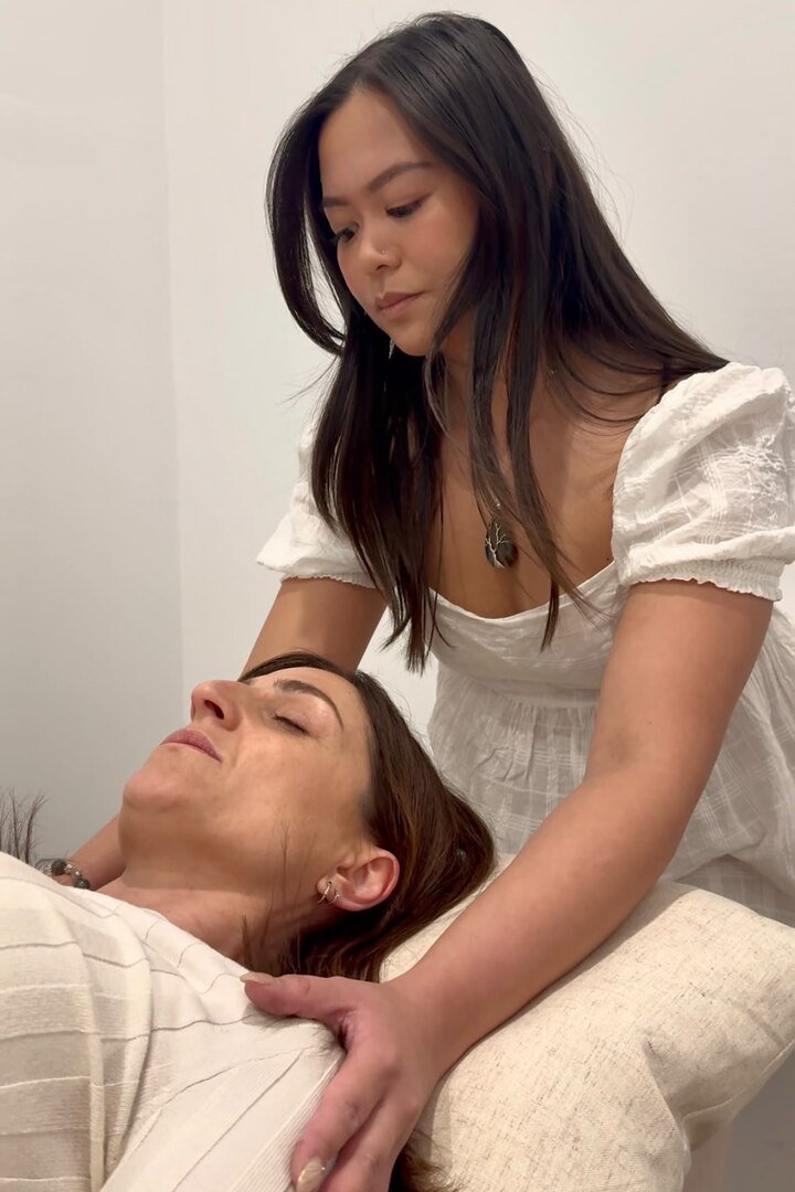 Sophia resting her hands on a client’s shoulders during a healing session.